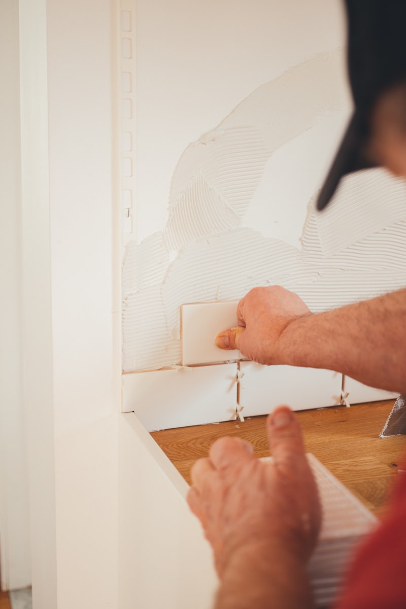 Hands setting wall tile with spacers during a remodel